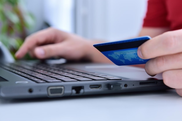 Mãos de empresário usando computador portátil e cartão de crédito azul