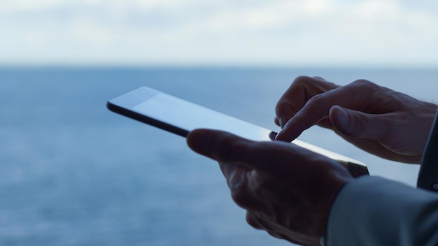 Mãos de empresário usando dispositivo tablet no conceito de tecnologia de escritório com vista para o mar