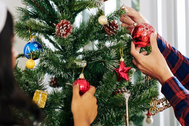 Mãos de empresários decorando a árvore de Natal no escritório com enfeites coloridos