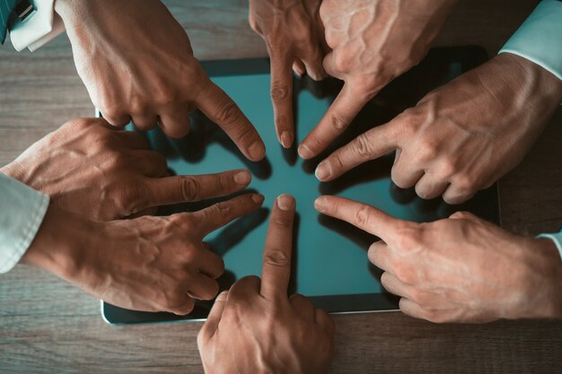 Foto mãos de empresários tocando a tela do tablet digital na mesa de madeira