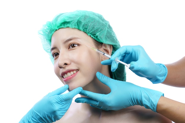 Mãos de esteticista injetando toxina botulínica A em uma mulher asiática na área dos olhos.