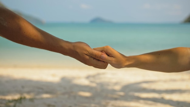 Mãos de flertar jovem e mulher tocando na praia do mar