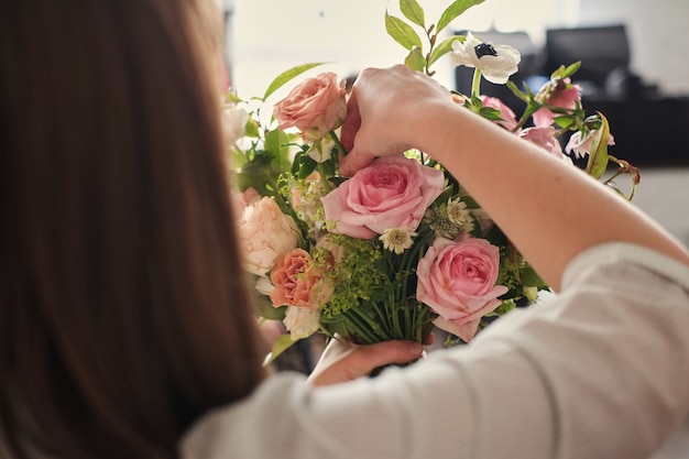 Mãos de florista coletar buquê de casamento. florista no trabalho