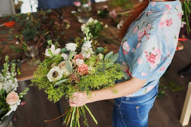 Mãos de florista coletar buquê de casamento. florista no trabalho