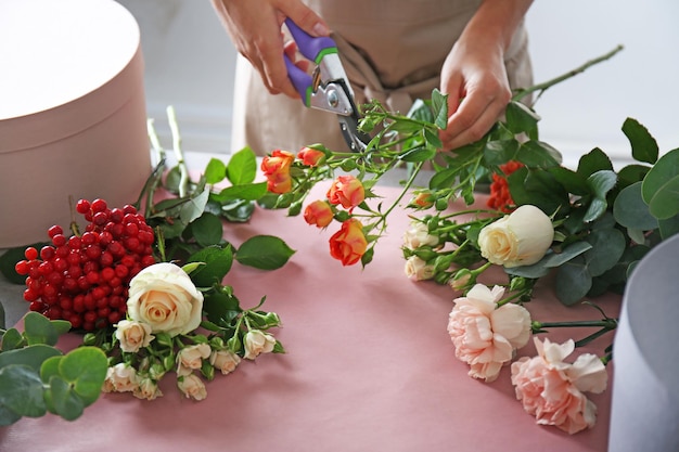 Mãos de florista feminina fazendo composição com flores em close