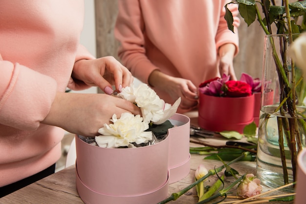 Mãos de florista feminina organizando composição floral