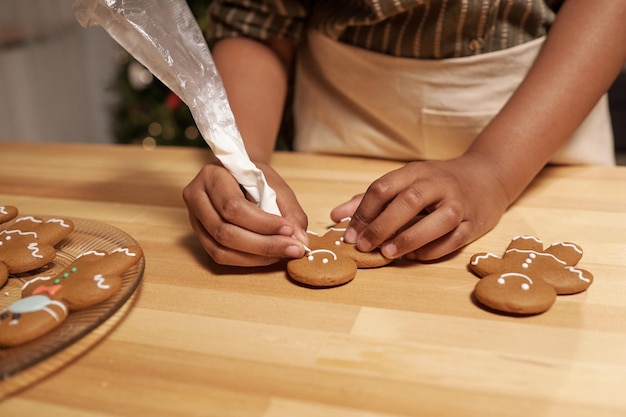 Mãos de garota africana cozinhando biscoitos de gengibre na mesa