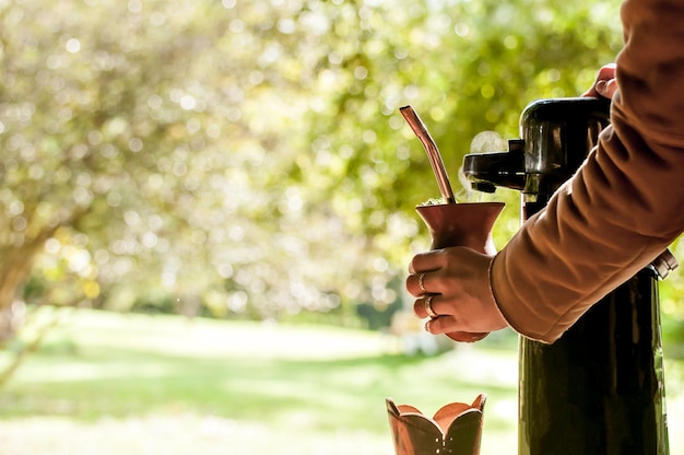 Mãos de gaúchos segurando e servindo chá mate de chimarrão chá típico do sul do Brasil