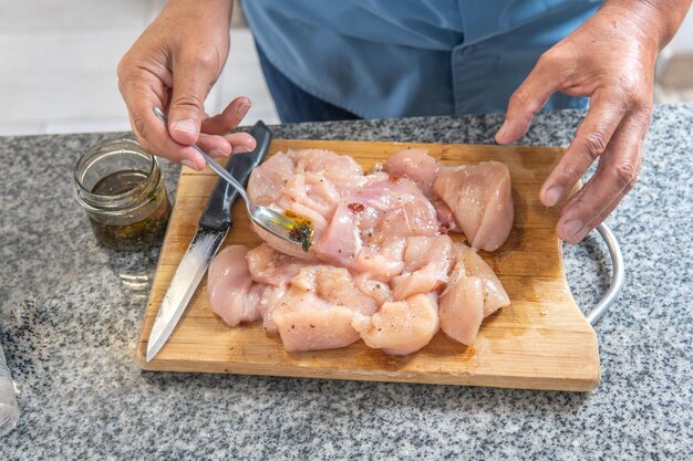 Foto mãos de homem colocando tempero em um frango cru para cozinhá-lo