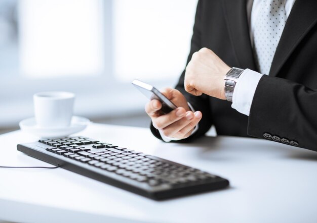 mãos de homem com teclado assistindo tempo e segurando smartphone