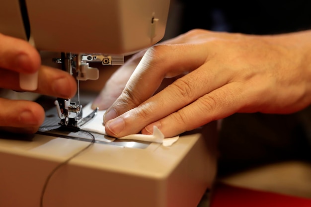 mãos de homem costurando na máquina de costura