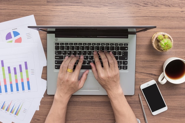 Mãos de homem de negócios usando o computador portátil na mesa