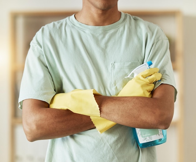 Foto mãos de homem e frasco de spray na limpeza doméstica ou remoção de bactérias e germes em casa closeup de empregada doméstica ou faxineira com braços cruzados de profissional no serviço doméstico em casa