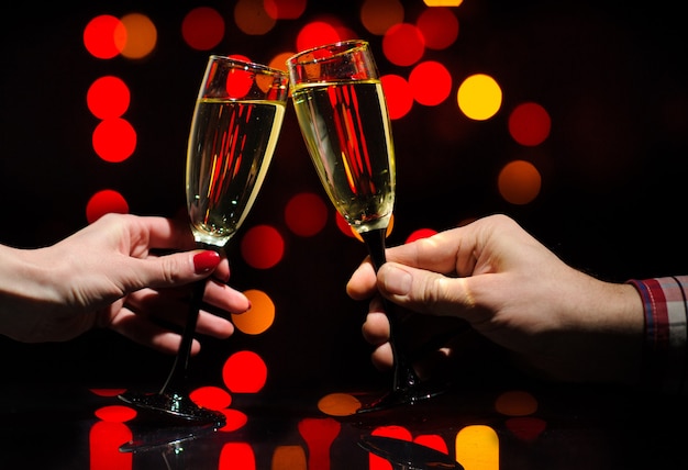 Mãos de homem e mulher com taças cheias de champanhe. felicidades.