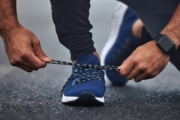 Foto mãos de homem e sapatos de gravata na estrada para corrida de fitness ou treino cardio no asfalto ao ar livre mão de corredor ou atleta masculino amarrando sapato e se preparando para treinamento esportivo na rua