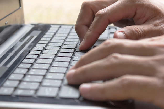 Mãos de homem está digitando laptop