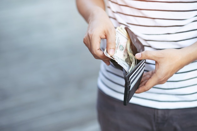 Foto mãos de homem hipster segurando uma carteira com cartões de crédito e uma pilha de dinheiro.