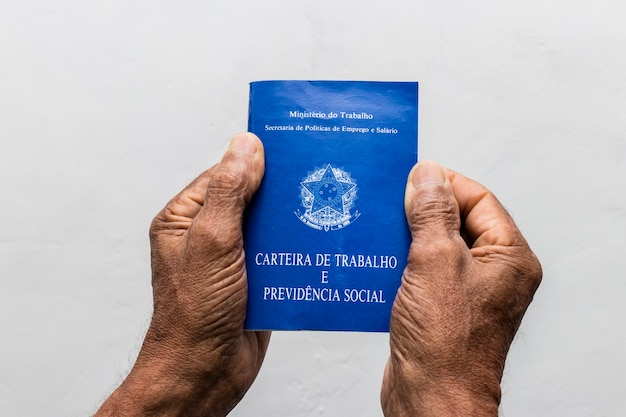 Mãos de homem negro sênior segurando pasta de trabalho, documento da previdência social brasileira