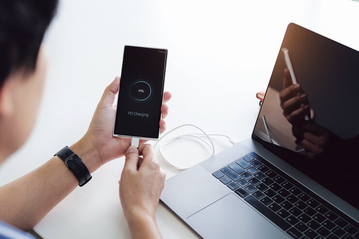 Foto mãos de homem segurando a bateria de carregamento do smartphone da porta c do notebook com o uso da tecnologia de carregamento pd