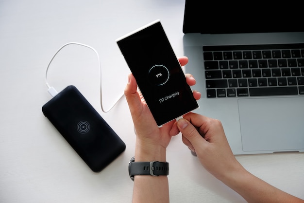 Mãos de homem segurando bateria de carregamento de smartphone de banco de energia externo com o uso de tecnologia de carregamento PD