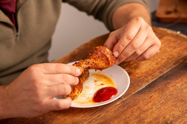 mãos de homem segurando uma coxa de frango na mesa
