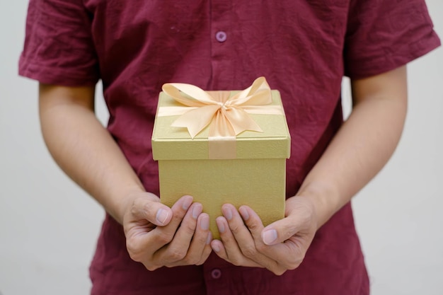 Foto mãos de homem segurando uma pequena caixa de presente de ouro embrulhada com fita de ouro