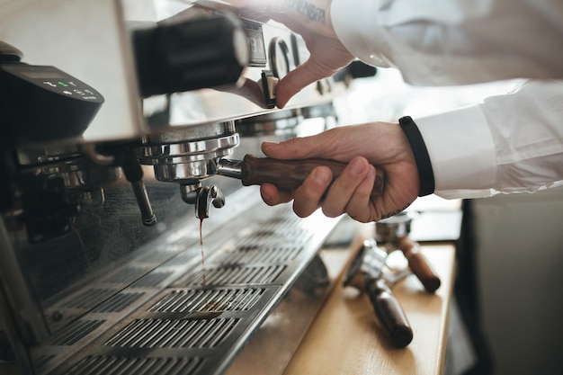 Mãos de homem trabalhando com máquina de café no café Feche as mãos de barista preparando café na cafeteria