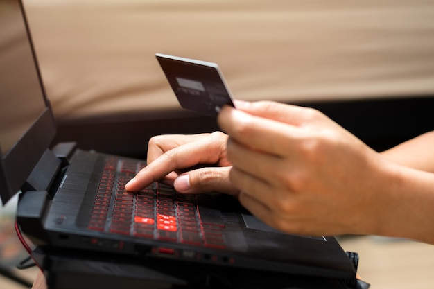 Foto mãos de homem usando computador portátil e segurando o cartão de crédito. compras online e conceito de pagamento online.