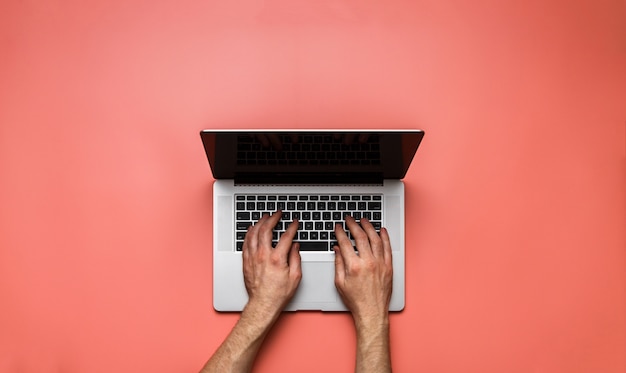 Foto mãos de homem usando o laptop na mesa-de-rosa