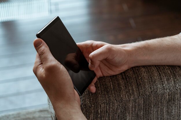 Mãos de homem usando smartphone na poltrona