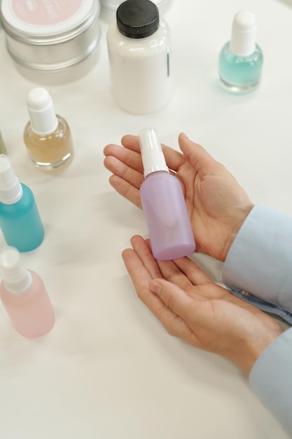 Mãos de jovem comprador feminino segurando garrafa de plástico com produto cosmético