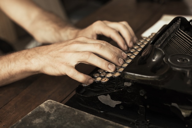 Mãos de jovem digitando em uma máquina de escrever vintage antiga