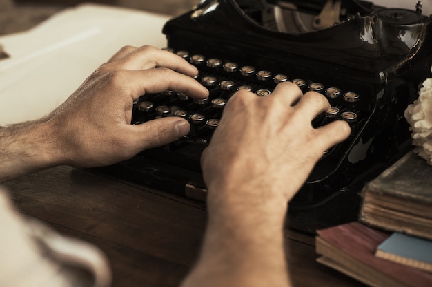 Foto mãos de jovem digitando em uma máquina de escrever vintage antiga