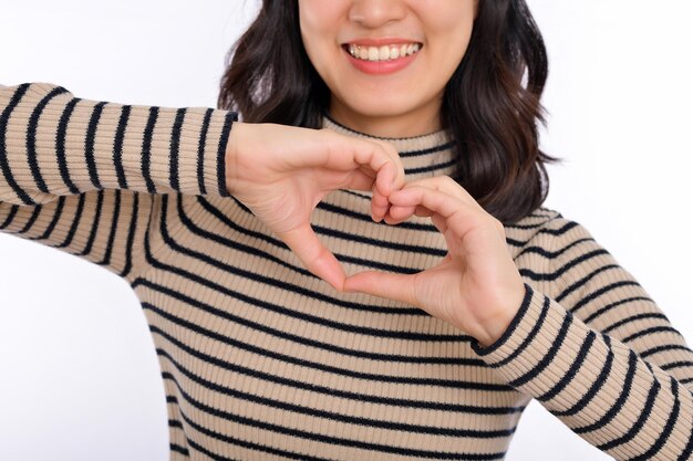 Mãos de jovens asiáticas fazendo forma de coração em um fundo branco e isolado