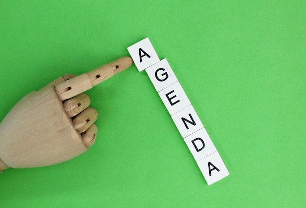 Mãos de madeira e alfabetos com a palavra agenda O conceito de agenda de hoje