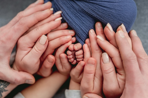 Mãos de mãe, pai e filho segurando os pés do bebê recém-nascido