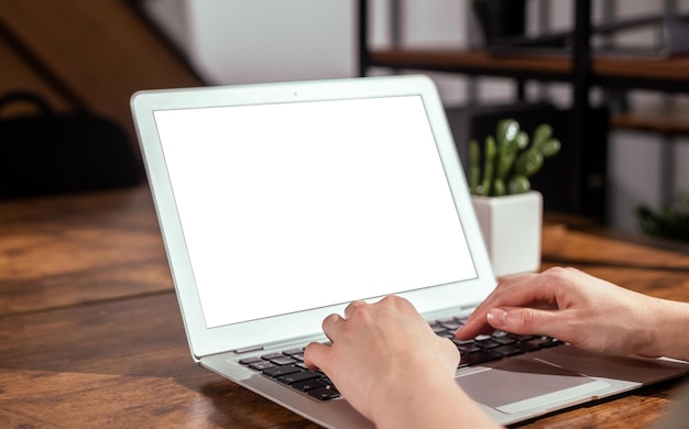 Mãos de maquete de tela de laptop digitando no teclado do computador PC com monitor branco em branco vazio na mesa do escritório