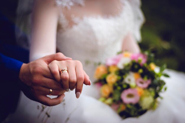 Mãos de marido e mulher com alianças de casamento mãos da noiva e do noivo