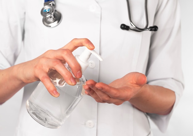 Mãos de médico aplicando desinfetante antibacteriano e lavando as mãos.