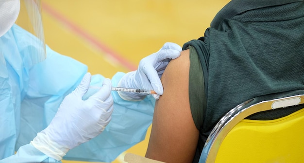 Mãos de médico closeup que está vacinando no braço de um jovem para dose de reforço anti covid19