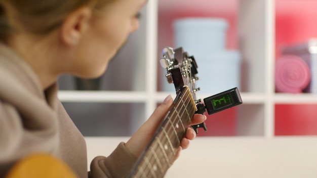 Mãos de menina closeup afinando guitarra Jovem mulher verificando pinos de guitarra acústica