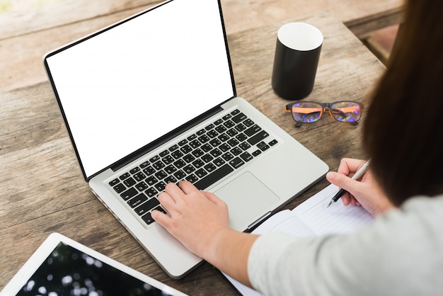 Mãos de menina. Laptop e xícara de chá na mesa de madeira