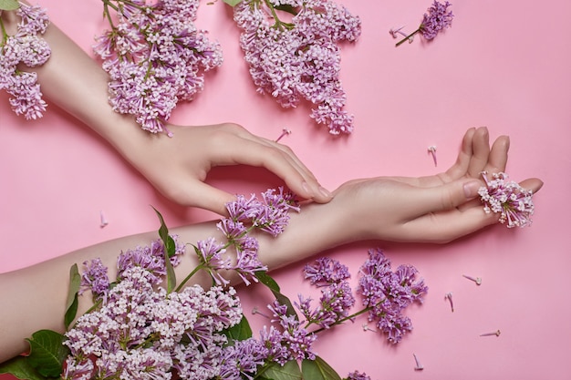 Mãos de modelo de moda com flores lilás roxas brilhantes