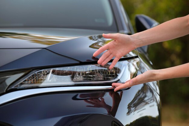 Mãos de motorista feminina verificando o farol de seu novo carro Compra do conceito de veículo