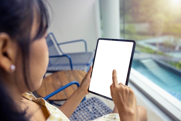 Mãos de mulher asiática fechadas segurando e apontando no tablet caminho de recorte na tela branca isolada comunicação de tecnologia social de compras on-line