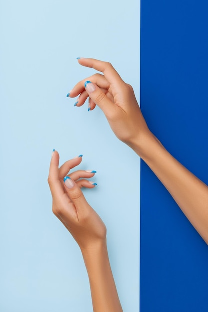 Mãos de mulher bonita com design de unhas na moda sobre fundo azul