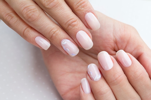 Mãos de mulher bonita preparada com unhas femininas na mesa cinza clara.