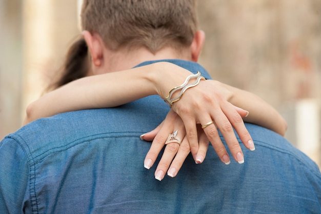 Mãos de mulher com a pulseira abraçando o pescoço do homem