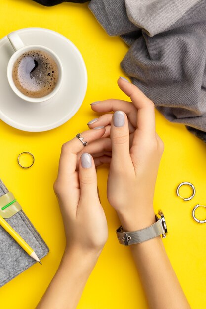 Mãos de mulher com manicure mínima em amarelo