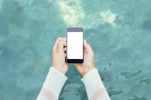 Mãos de mulher com telefone celular em branco em um fundo de superfície de água simulado